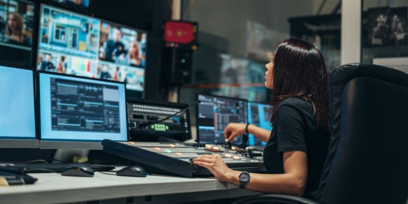 A young person is pictured from the side as they edit footage in a TV production studio.