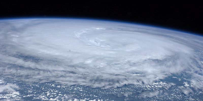 Clouds forming a hurricane in a picture taken from space. which has been taken from space. They form a large swirling mass.