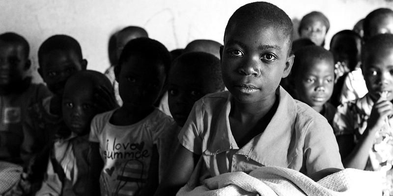 Picture shows a group of young children sitting in a classroom