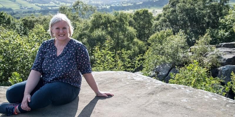 Picture shows Professor Cath Noakes sitting on a rocky outcrop onto of a Yorkshire moor