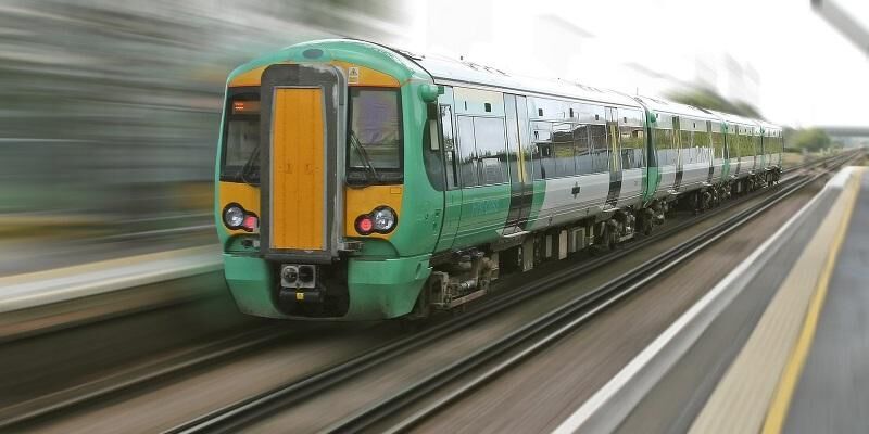 The image shows a commuter train rapidly moving through a station