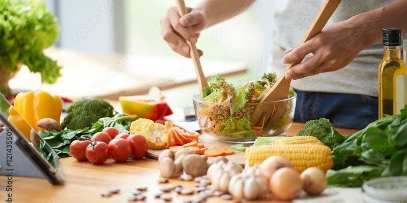 A cook mixes a bowl of freshly prepared vegetables