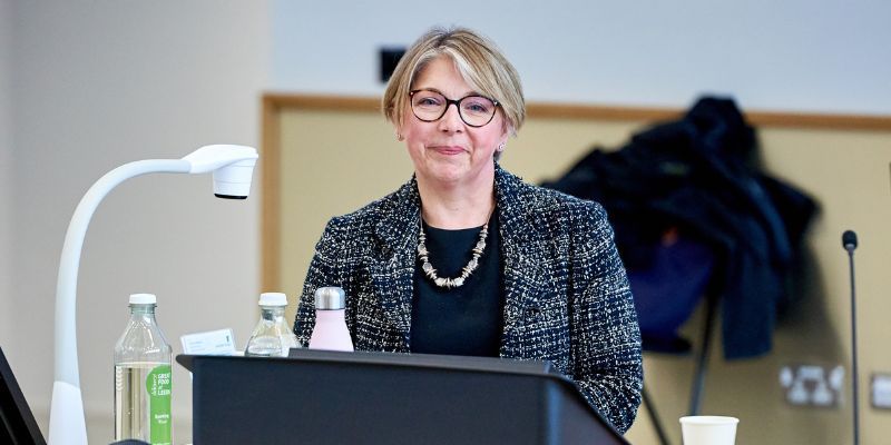 Sarah Breedon speaks at a podium in a University of Leeds lecture theatre.