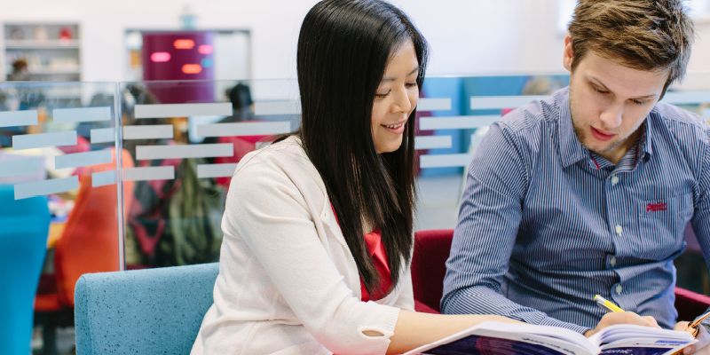 Two students look at a book.