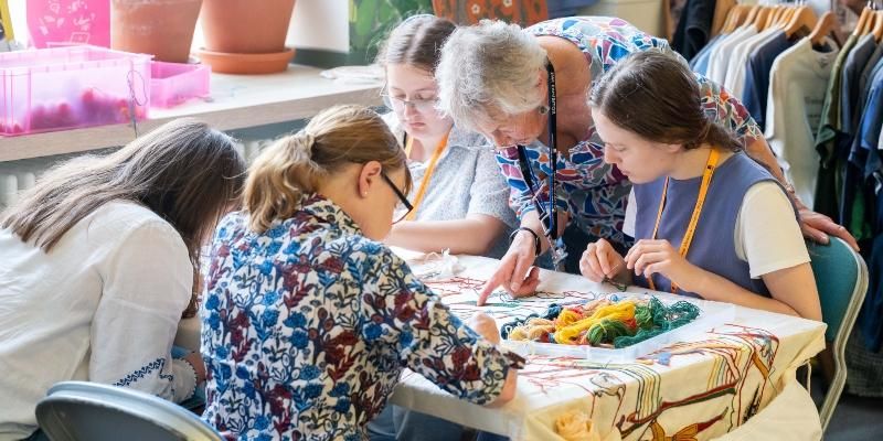Artist Tina Greene demonstrates to visitors what stitches to use on the Battle Tapestry.