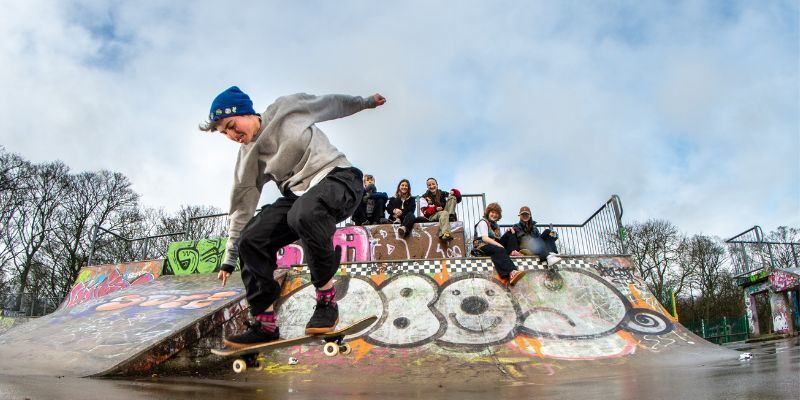 A young skateboarder does tricks on a board as a group of friends look on