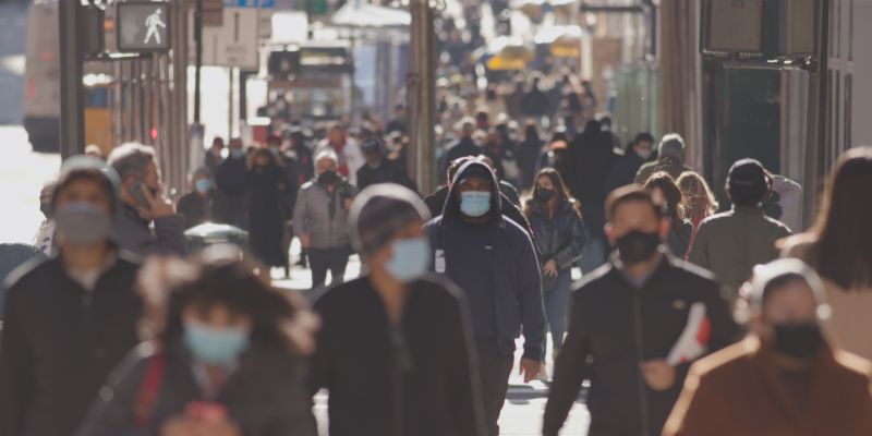 Anonymous crowd of people walking street wearing masks during covid 19 coronavirus pandemic