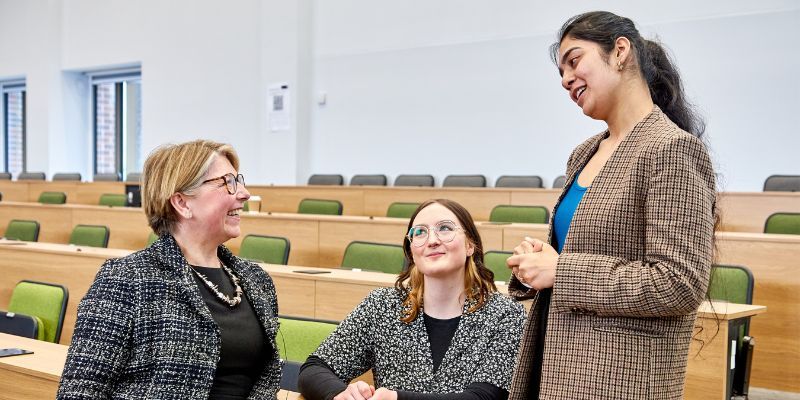 Sarah Breeden speaks to two female students in a lecture hall