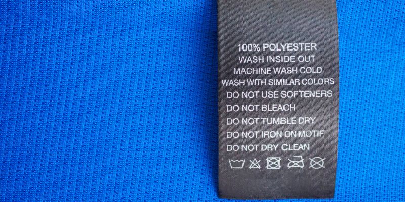 Black laundry care washing instructions clothes label on blue jersey polyester sport shirt