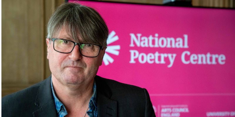 Professor Simon Armitage with the National Poetry Centre logo on a pink slide