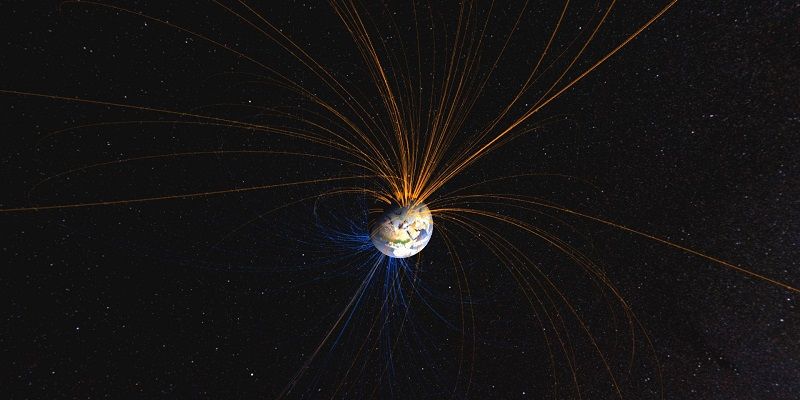 Earth floating small in vast black space with lines radiating out from it to illustrate magnetic field