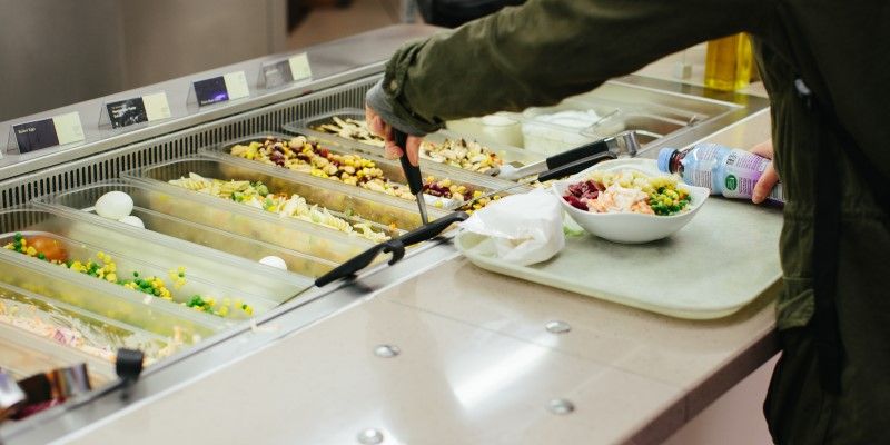 A student selecting food from a cafeteria selection