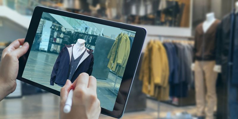 Hand holding a tablet showing an image of clothes