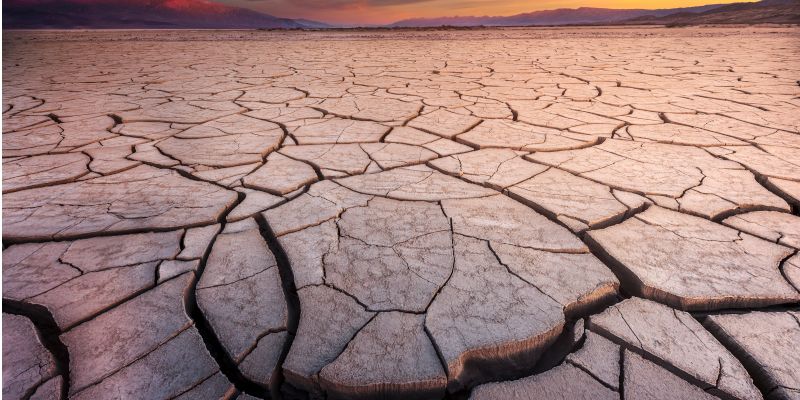 close up of dry, deeply cracked river bed with hills on the horizon