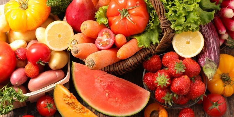 A range of fruits and vegetables in a basket and laying on the ground