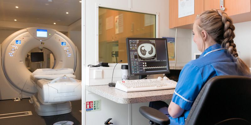 Nurse looking at computer near CT scanner