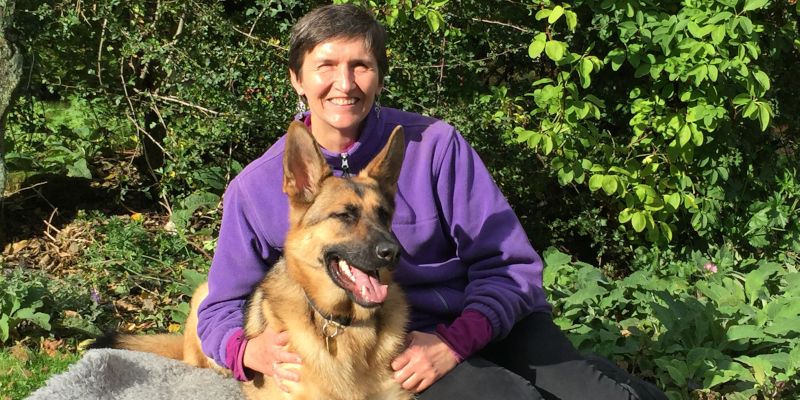 Professor Anna Lawson sitting on a rug outdoors with guide dog Finn.