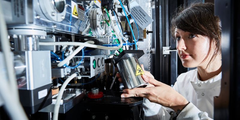 Student in lab handling canister amid science facilities.