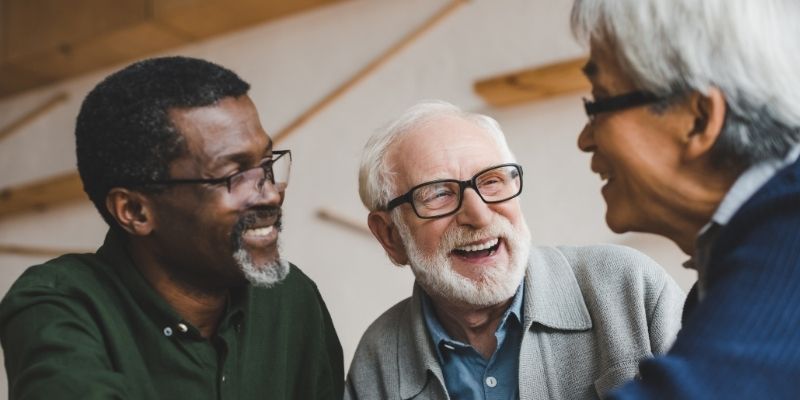 Three elderly people talking to each other and smiling.