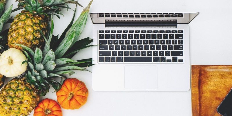 A top-down view showing fresh fruit and vegetables next to an open laptop.