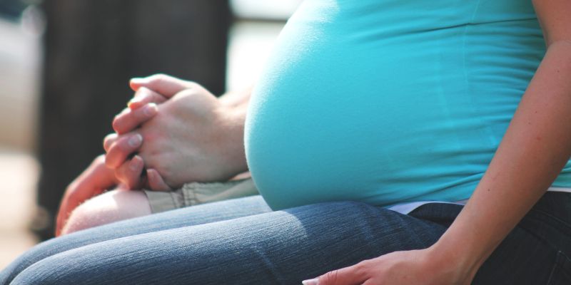 A close up of a pregnant person holding their partner's hand