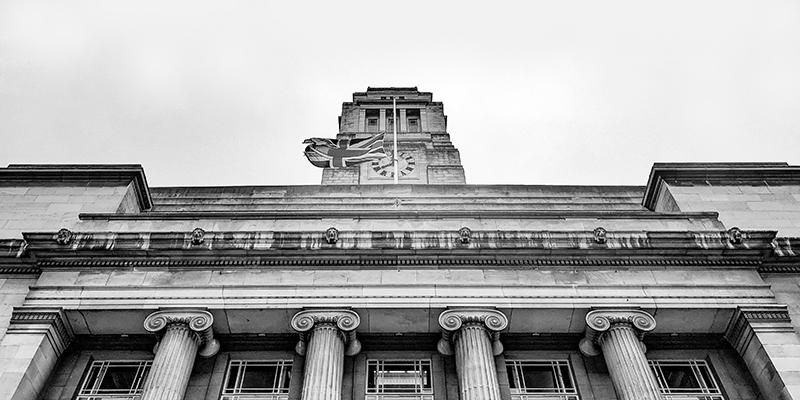 A greyscale image of the Parkinson Buiding with a British flag flying from it.