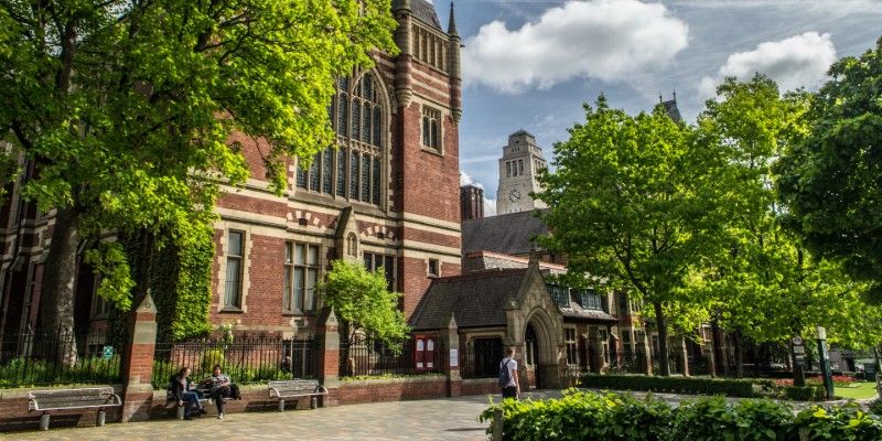 The Great Hall on a sunny day surrounded by green trees with the Parkinson Building in the distance.