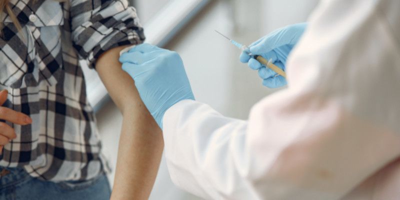 A medic using a syringe to administer a vaccine into a patient's upper arm.