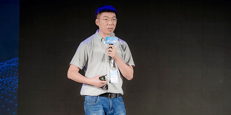 Man speaking into a microphone in front of a black background