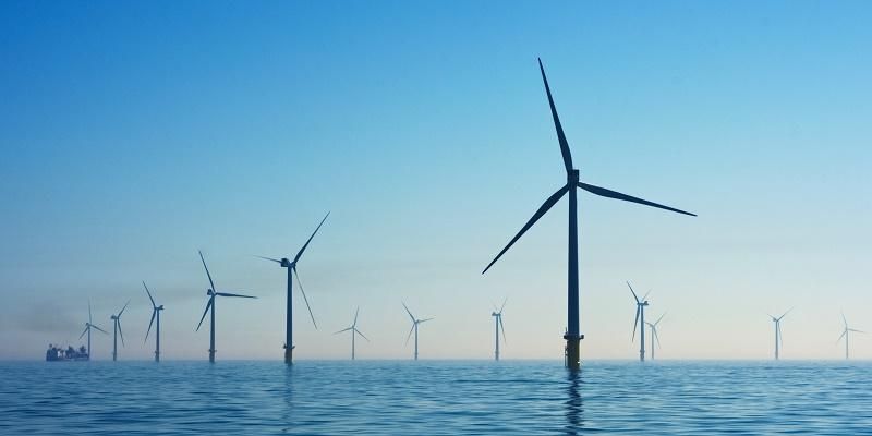 Off-shore wind turbines, with blue sky and sea in the background