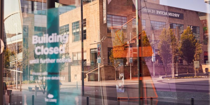 The Lowry in lockdown - a building reflected in glass door showing a closed sign in the window.