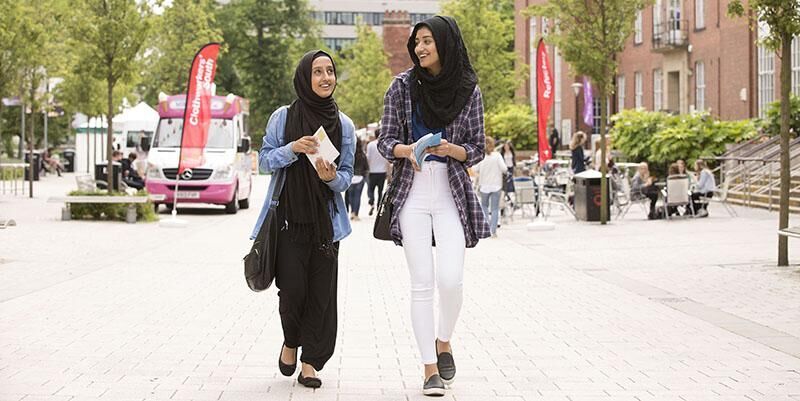 Two students walking together on an open day outside Leeds University Union.