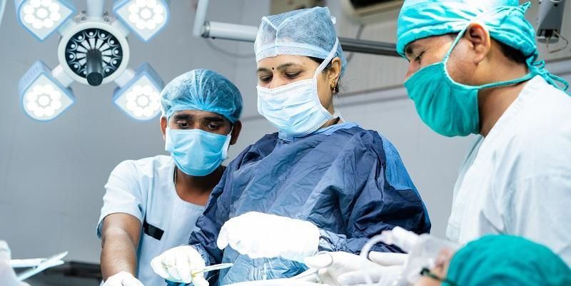 Three members of an operating team working together on an unseen patient