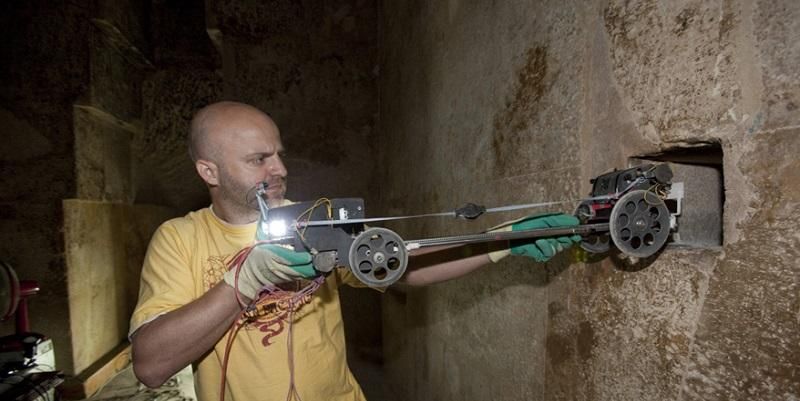 The image shows the compavt robotic system being put into the passageway that starts at the Queen's Chamber in the Great Pyramid.