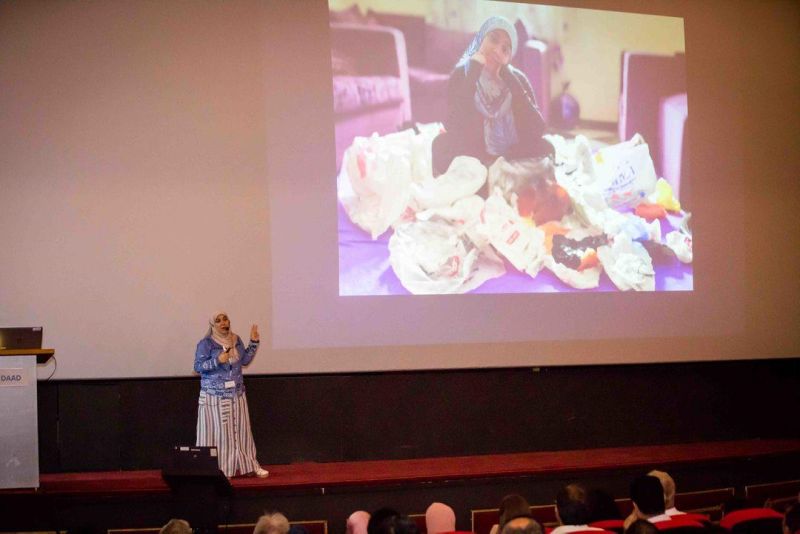 Aya stands on stage, presenting to delegates in an audience