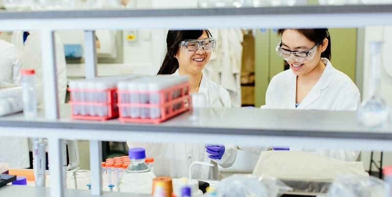 Two scientists smiling together as they work in a laboratory.