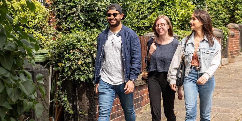 Three students in conversation walking down a street in Leeds.