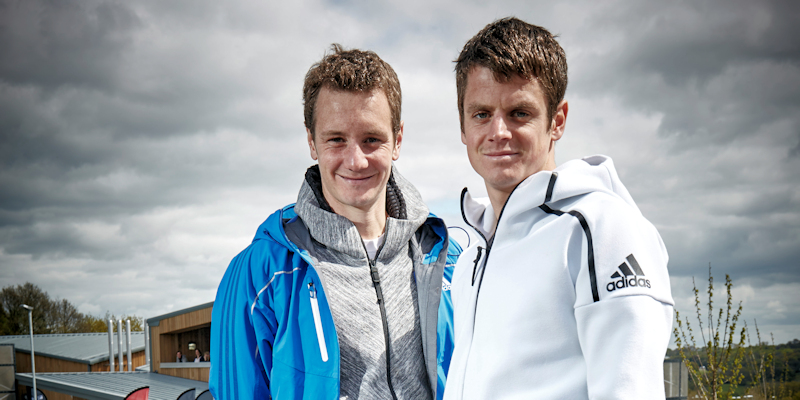 Alistair and Jonny Brownlee smiling and looking at the camera outside the Brownlee Centre at the University of Leeds