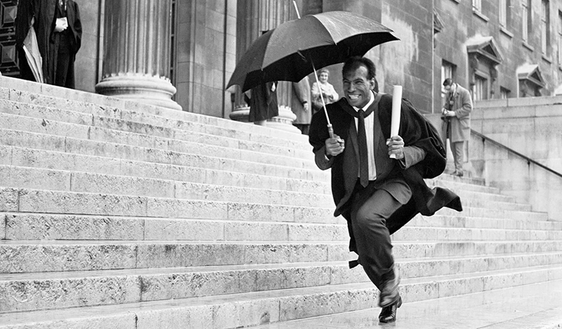 Cec Thompson running on the Parkinson steps holding an umbrella and a scroll.