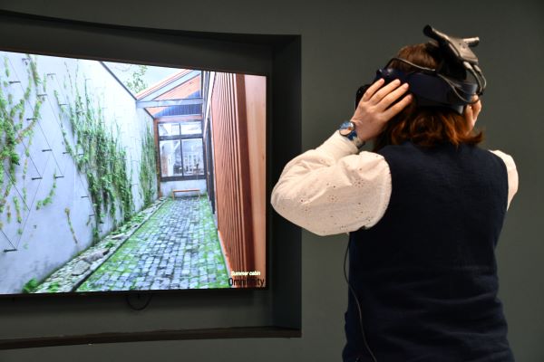 A person is trying on a VR headset in front of a screen