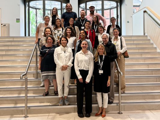 A large group of 19 people stood on the steps in the entrance foyer of the Esther Simpson Building at University of Leeds