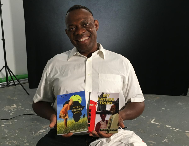 Brian Kokoruwe sits holding two of his books