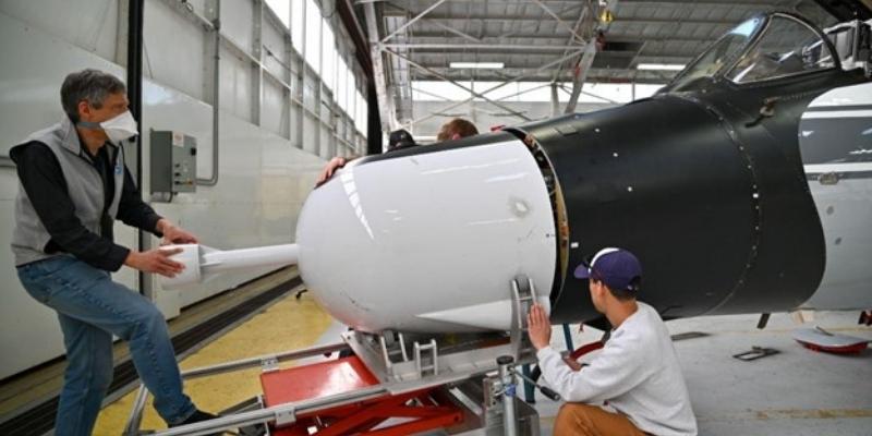 Scientists install equipment on the nose of an aircraft