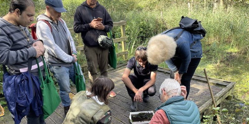Members of Mafwa theatre and University of Leeds academics gather around a tray to examine what they pulled out of the bog in nets