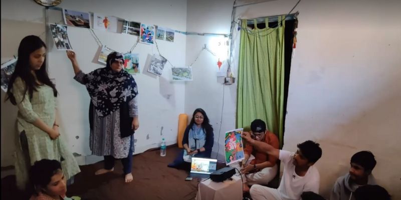 A community group discusses what sustainability could look like in their local area. Ideas are hung up on the wall and one person is holding up an artwork that says 'Save the planet, save the joy'