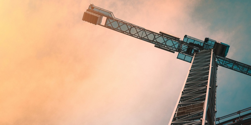 A crane next to a building which is under construction.
