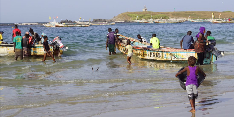 Villagers pushing small fishing boats out to sea on the coast of Dakar.