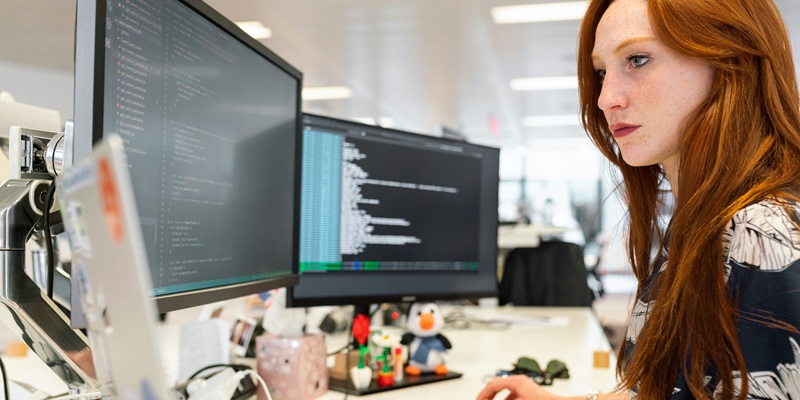 A person in a bright office, using a computer with several screens