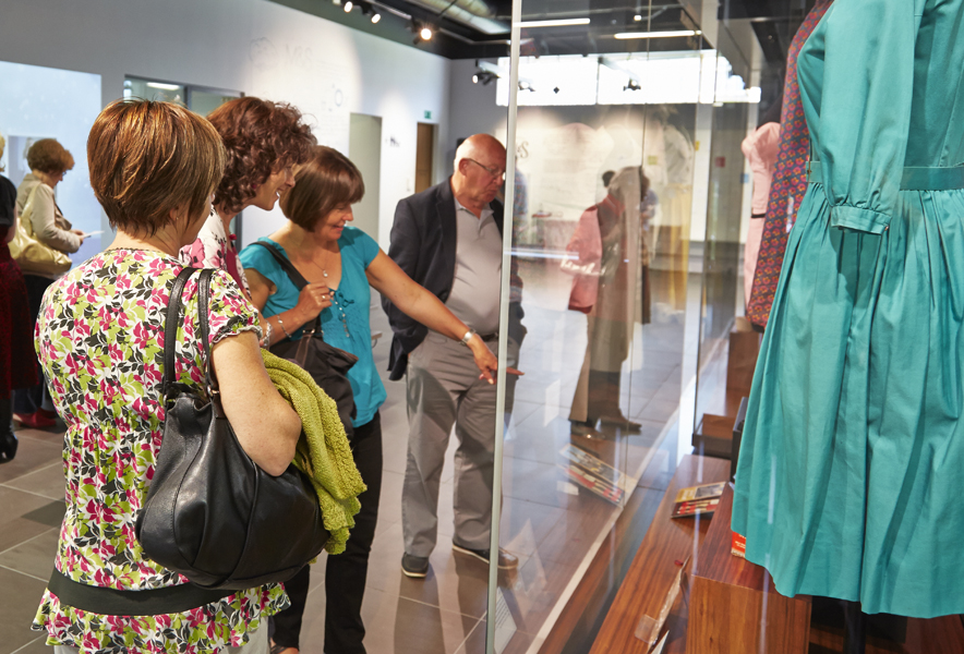 Visitors look at clothing in display cases at the Marks & Spencer Company archive