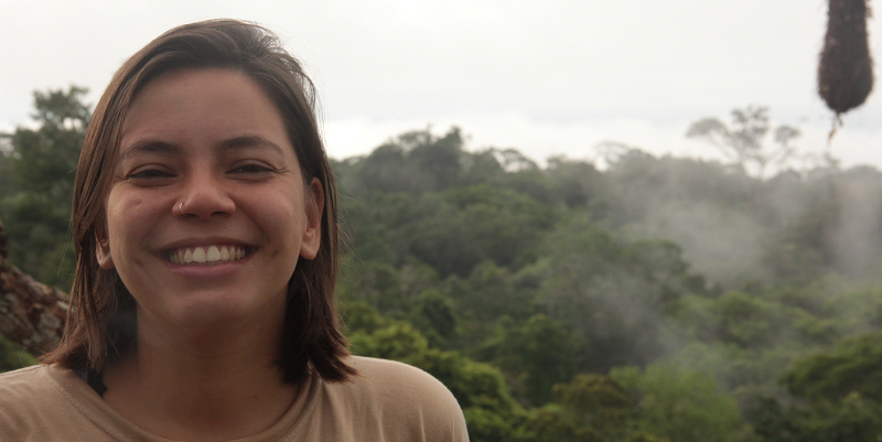 A photo Dr Julia Tavares with the forest in the background.